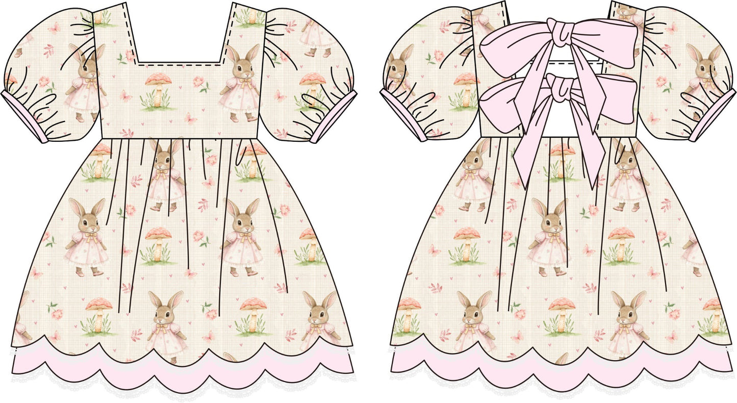 Two children's dresses with bunny pattern and bow details on a white background